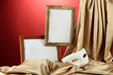 Beyaz maske, boş çerçeveler ve kırmızı zemin üzerine altın ipek kumaş