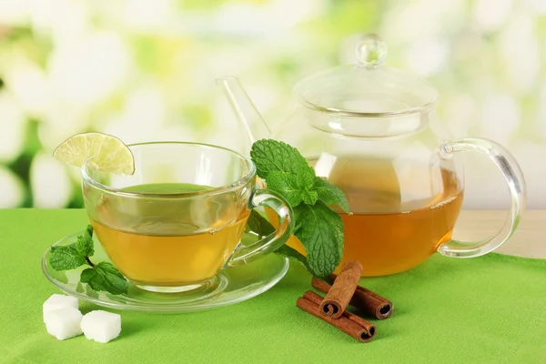 Taza de té con menta, lima y canela sobre la mesa sobre fondo brillante — Foto de Stock