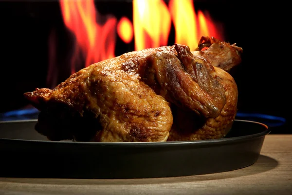 Pollo asado entero en plato, sobre fondo de llama — Foto de Stock