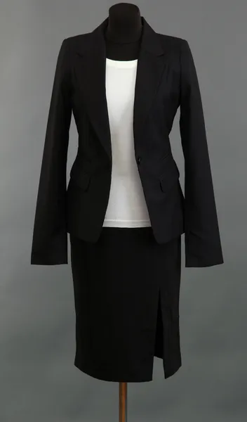 Белая блузка и черная юбка с пальто на манекене на сером фоне — стоковое фото