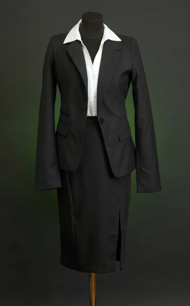 Белая блузка и черная юбка с пальто на манекене на темном фоне — стоковое фото