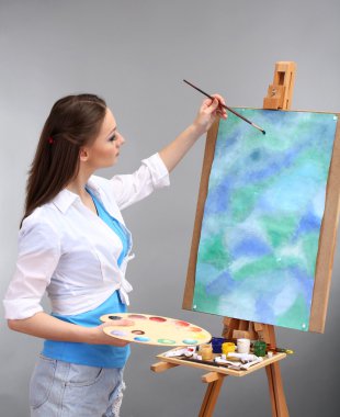 güzel bir genç kadın ressam gri arka plan üzerinde iş başında