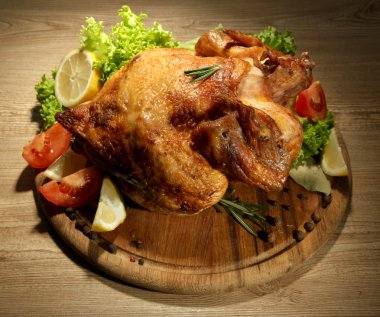 ahşap masa üzerinde plaka üzerinde sebze ile bütün kavrulmuş tavuk