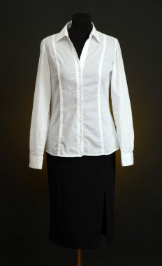 Beyaz bluz ve manken üzerinde koyu renk arka plan üzerinde siyah etek