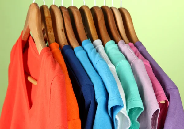 Variedad de camisas casuales en perchas de madera, sobre fondo azul — Foto de Stock