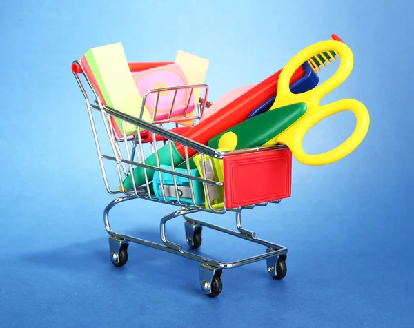 Trolley mit Schulausrüstung auf blauem Hintergrund — Stockfoto