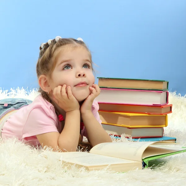 Carina bambina con libri colorati, su sfondo blu — Foto Stock