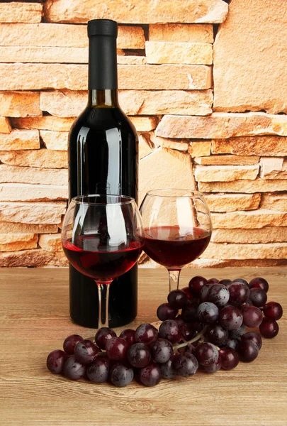 Composición de vino y uvas en la mesa sobre fondo de pared de ladrillo — Foto de Stock