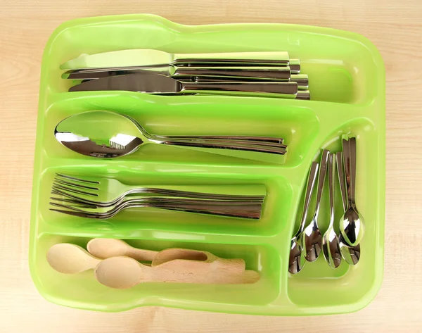 Vassoio di posate in plastica verde con posate a quadretti e cucchiai di legno sul tavolo di legno — Foto Stock