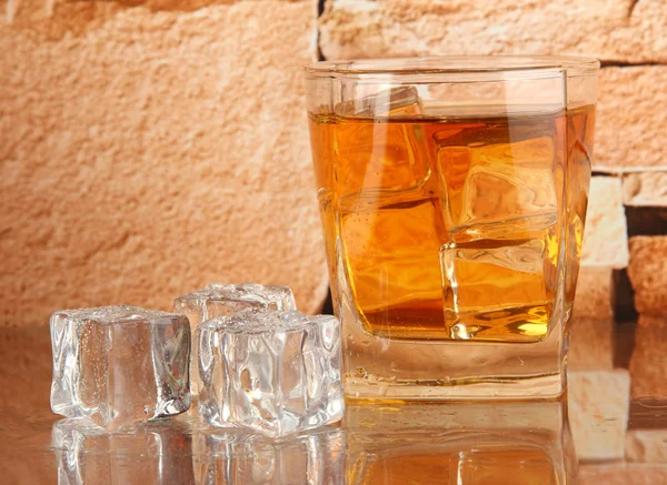 Glas whiskey och is på tegel vägg bakgrund — Stockfoto