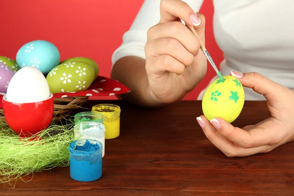 Mujer joven pintando huevos de Pascua, sobre fondo de color — Foto de Stock