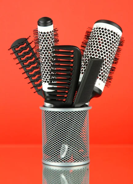 Iron basket with combs and round hair brushes, on color background — Stock Photo, Image