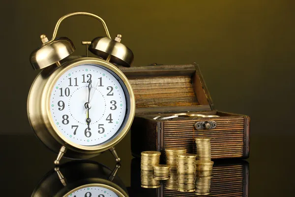 Reloj despertador con monedas en el pecho sobre fondo oscuro —  Fotos de Stock