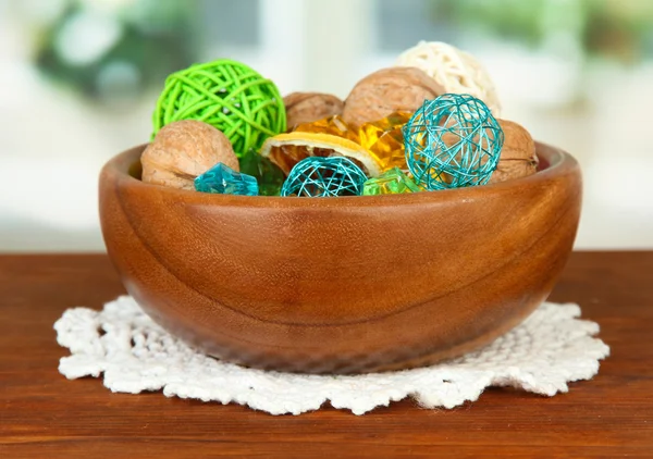 Dried oranges, wicker balls and other home decorations in wooden bowl, on bright background — Stock Photo, Image
