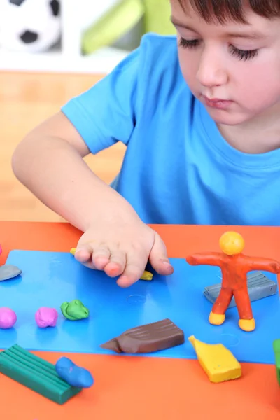 Cute little boy moulds from plasticine on table — Stock Photo, Image