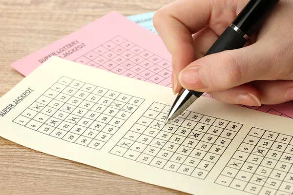 Closeup of lotto ticket during the marking of numbers, on wooden background — Stock Photo, Image