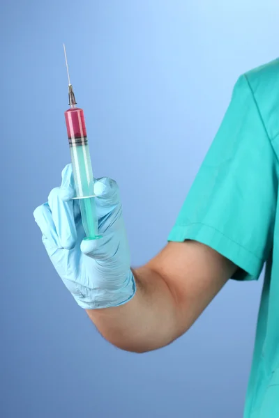 Doctor with syringe on blue background — Stock Photo, Image