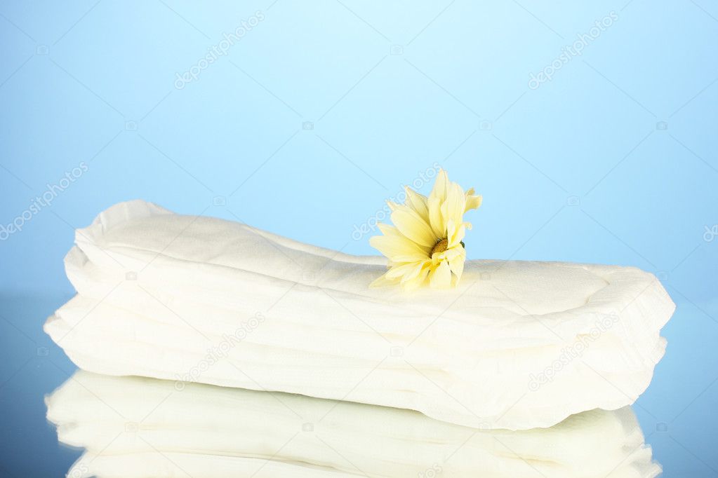 Panty liners and yellow flower on blue background close-up