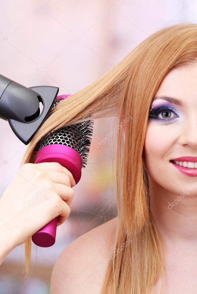 Beautiful woman and hands with hairdryer in beauty salon