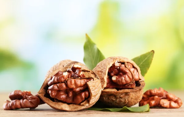 Nueces con hojas verdes, sobre fondo verde — Foto de Stock