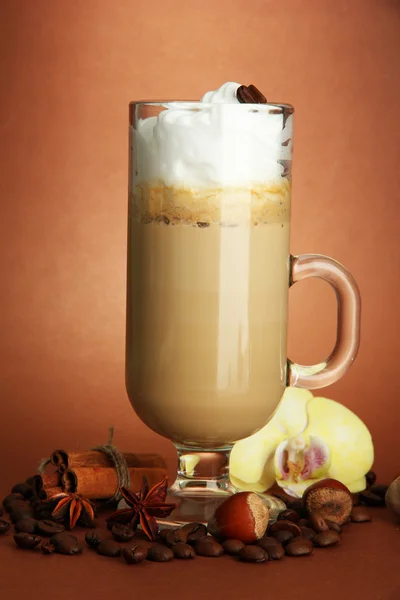 Café con leche fragante en taza de vidrio con especias, sobre fondo marrón —  Fotos de Stock