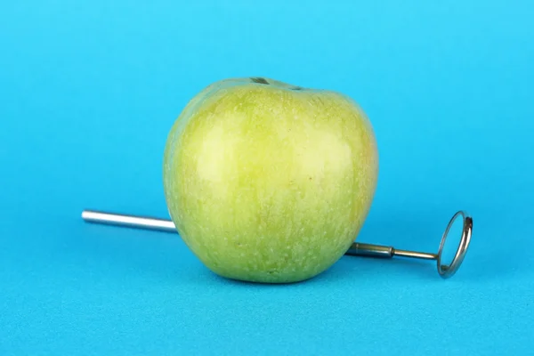 Green apple and dental tool on color background — Stock Photo, Image