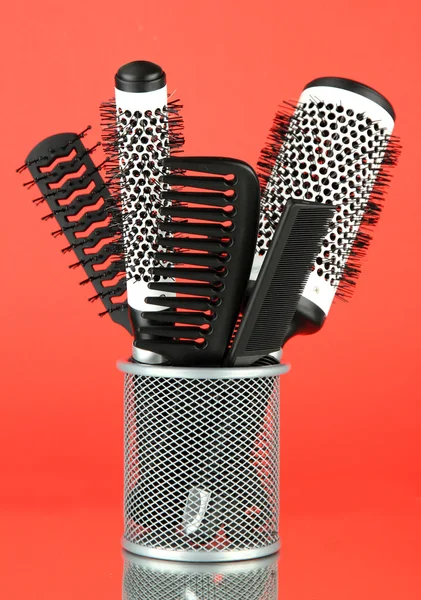 Iron basket with combs and round hair brushes, on color background — Stock Photo, Image