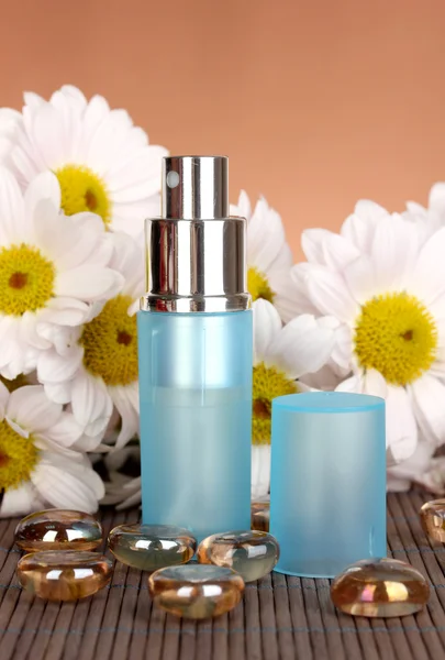 Women's perfume in beautiful bottle with camomiles on brown background — Stock Photo, Image