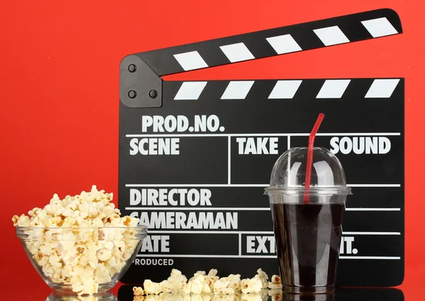 Film Filmklapper, cola en popcorn op rode achtergrond — Stockfoto