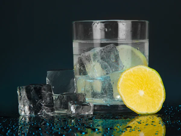 Isbitar i glaset med citron på Mörkblå bakgrund — Stockfoto