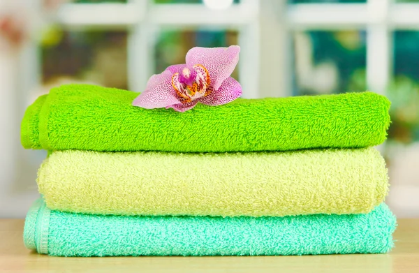 Stack of towels with fragrant flower on window background — Stock Photo, Image