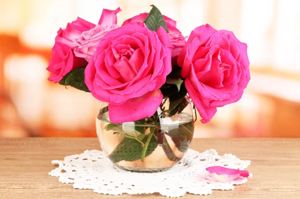 Beautiful pink roses in vase on wooden table on room background — Stock Photo, Image