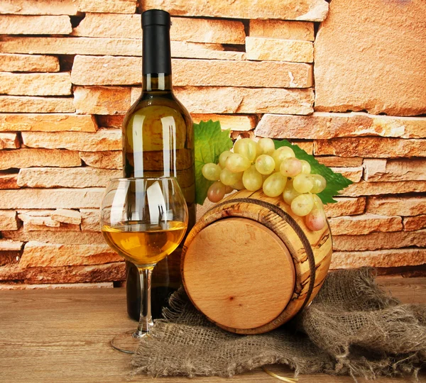 Composição de vinho e uvas em barril de madeira na mesa no fundo da parede de tijolo — Fotografia de Stock