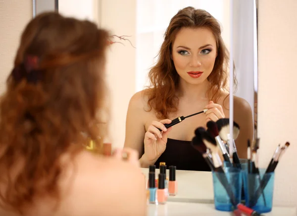 Junge schöne Frau schminkt sich in Spiegelnähe — Stockfoto