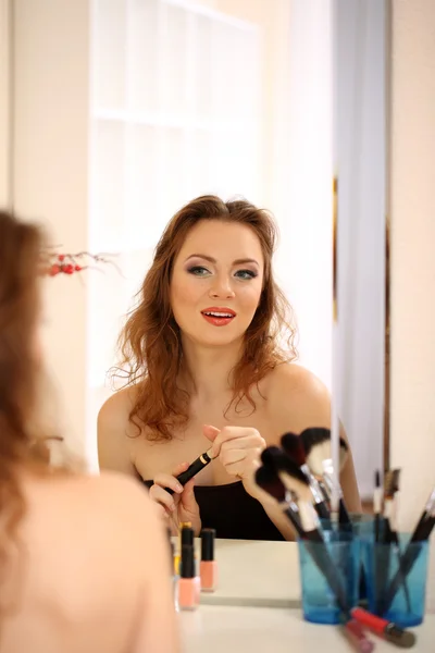 Jong mooi vrouw maken make-up in de buurt spiegel — Stockfoto