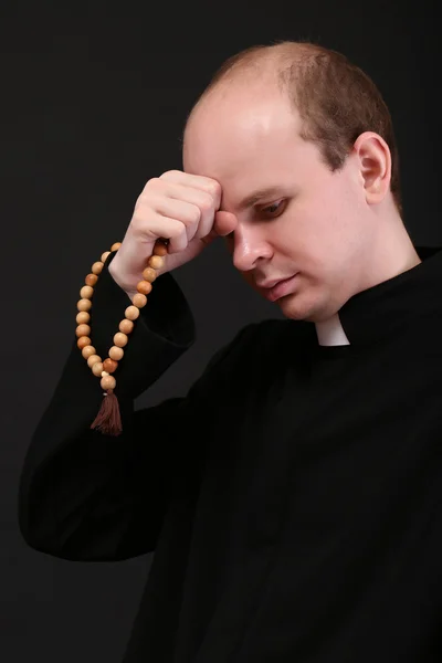 Joven pastor con rosario de madera, aislado en negro — Foto de Stock