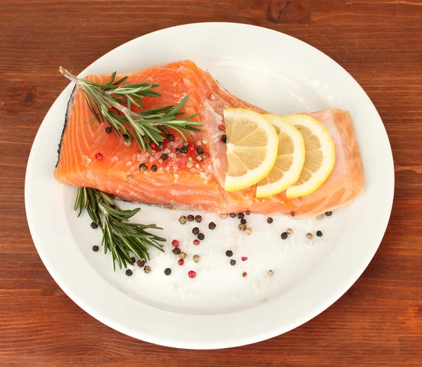 Fresh salmon fillet with herbals and lemon slices on plate,on wooden background — Stock Photo, Image