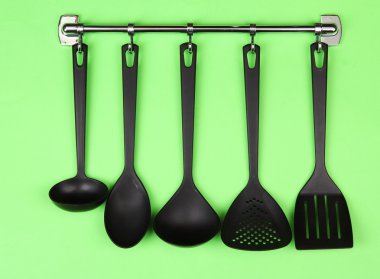 Gümüş kanca, yeşil arka plan üzerinde siyah mutfak gereçleri