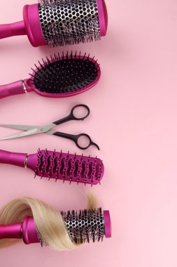 Fırçalar, pembe bir arka plan üzerinde kesme makası ve saç tarağı