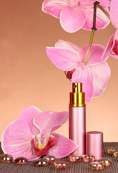 Women's perfume in beautiful bottle with orchids on brown background — Stock Photo, Image