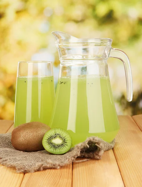 Fullt glas och kanna kiwi juice och kiwi på träbord utomhus — Stockfoto