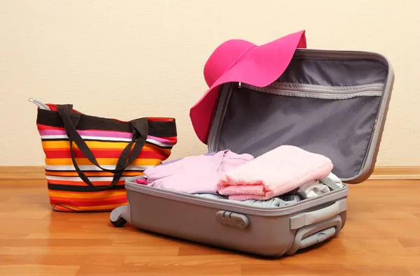 Open silver suitcase with clothing in room — Stock Photo, Image