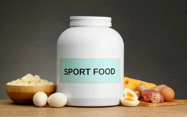 jar of protein powder and food with protein, on grey background