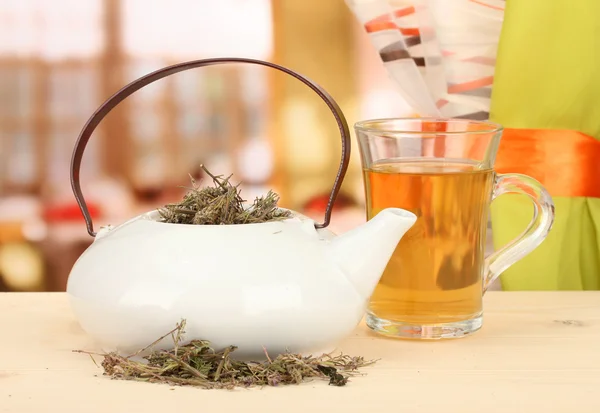 Dried herbs in teapot on wooden table, on bright background. Conceptual photo of herbal tea. — Stock Photo, Image