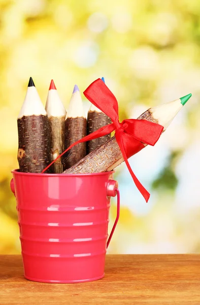 Colorful wooden pencils in pail on wooden table on bright background — Stock Photo, Image