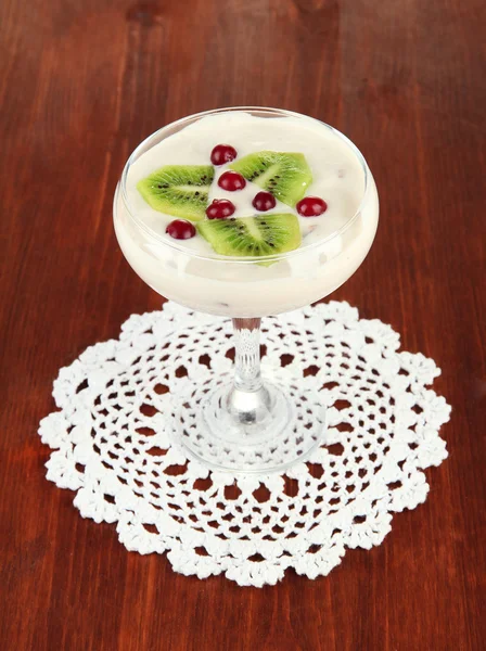 Glass of yoghurt dessert with fruits and berries, on wooden background — Stock Photo, Image