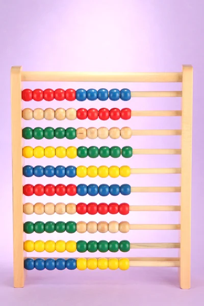 Abacus de brinquedo de madeira brilhante, no fundo roxo — Fotografia de Stock