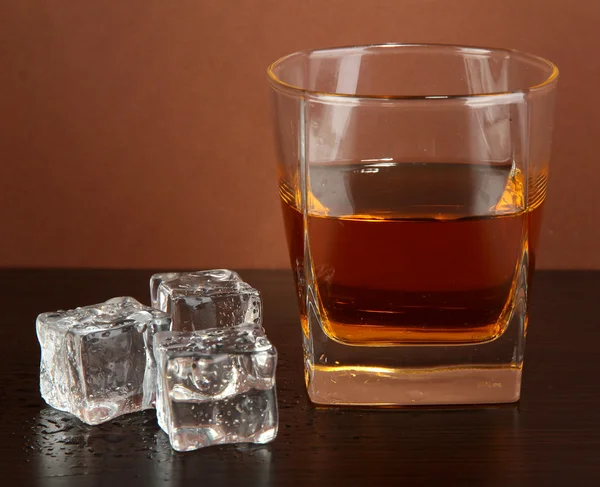 Glas whisky en ijs op bruine achtergrond — Stockfoto