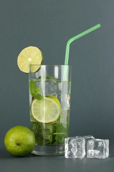 Glas vatten med is, mynta och lime på grå bakgrund — Stockfoto