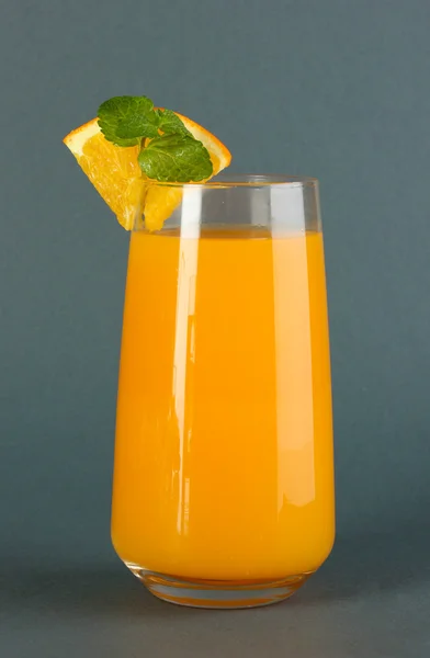 Glass of orange juice with mint and orange on grey background — Stock Photo, Image